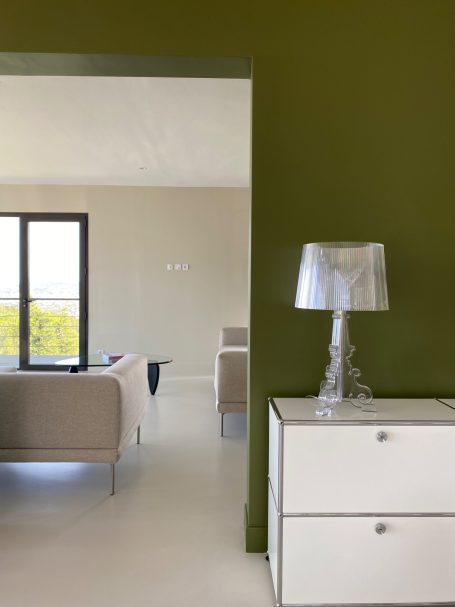 Intérieur moderne avec un mur vert, lampe et mobilier élégant.